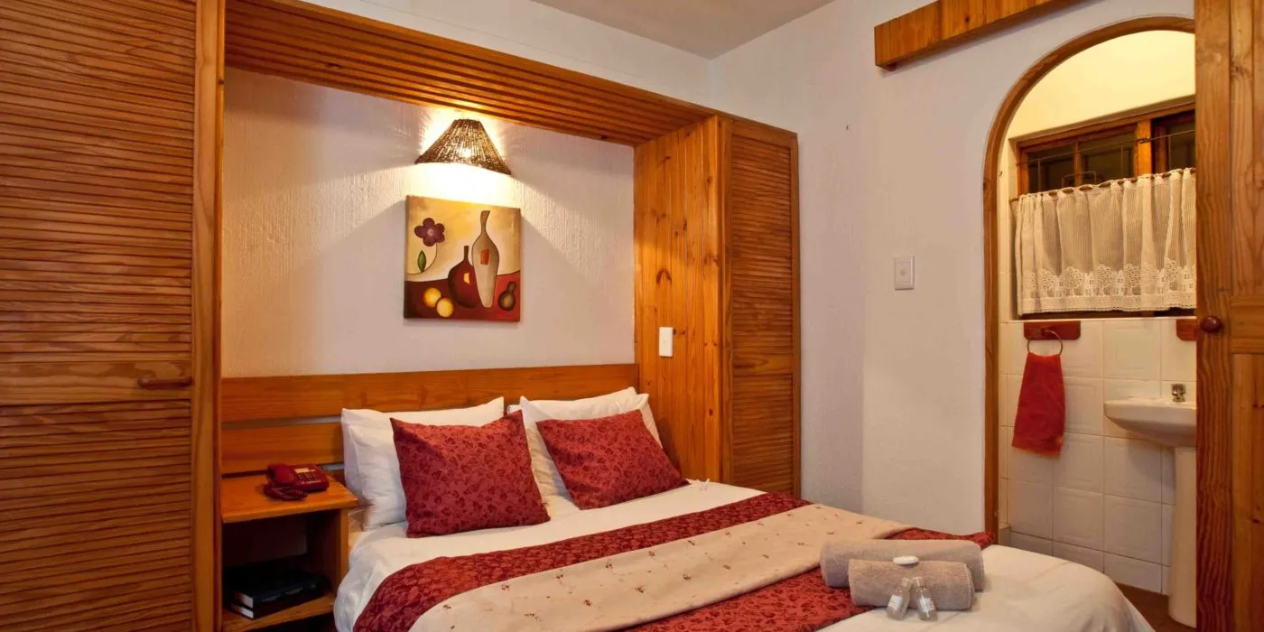 Cozy bedroom with wooden accents double bed and adjacent bathroom