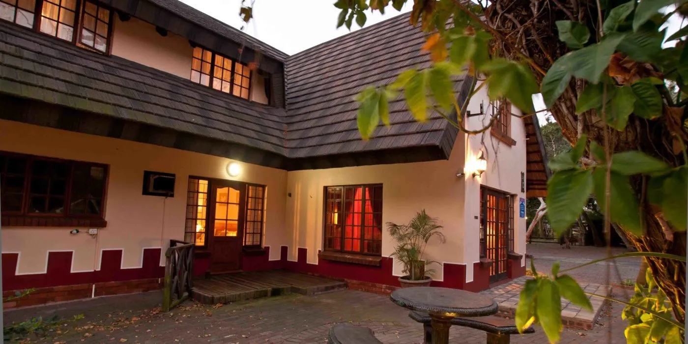 Cozy house with lit windows and surrounding greenery at dusk