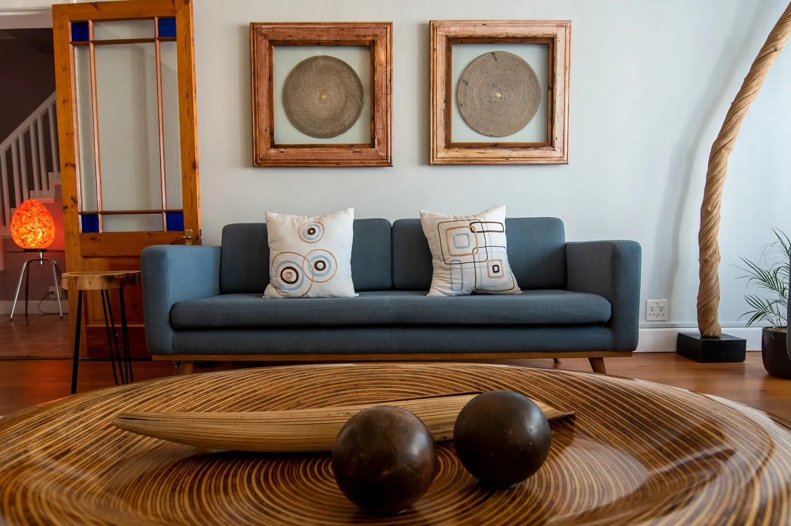 Blue sofa with patterned pillows wooden art and a wooden coffee table