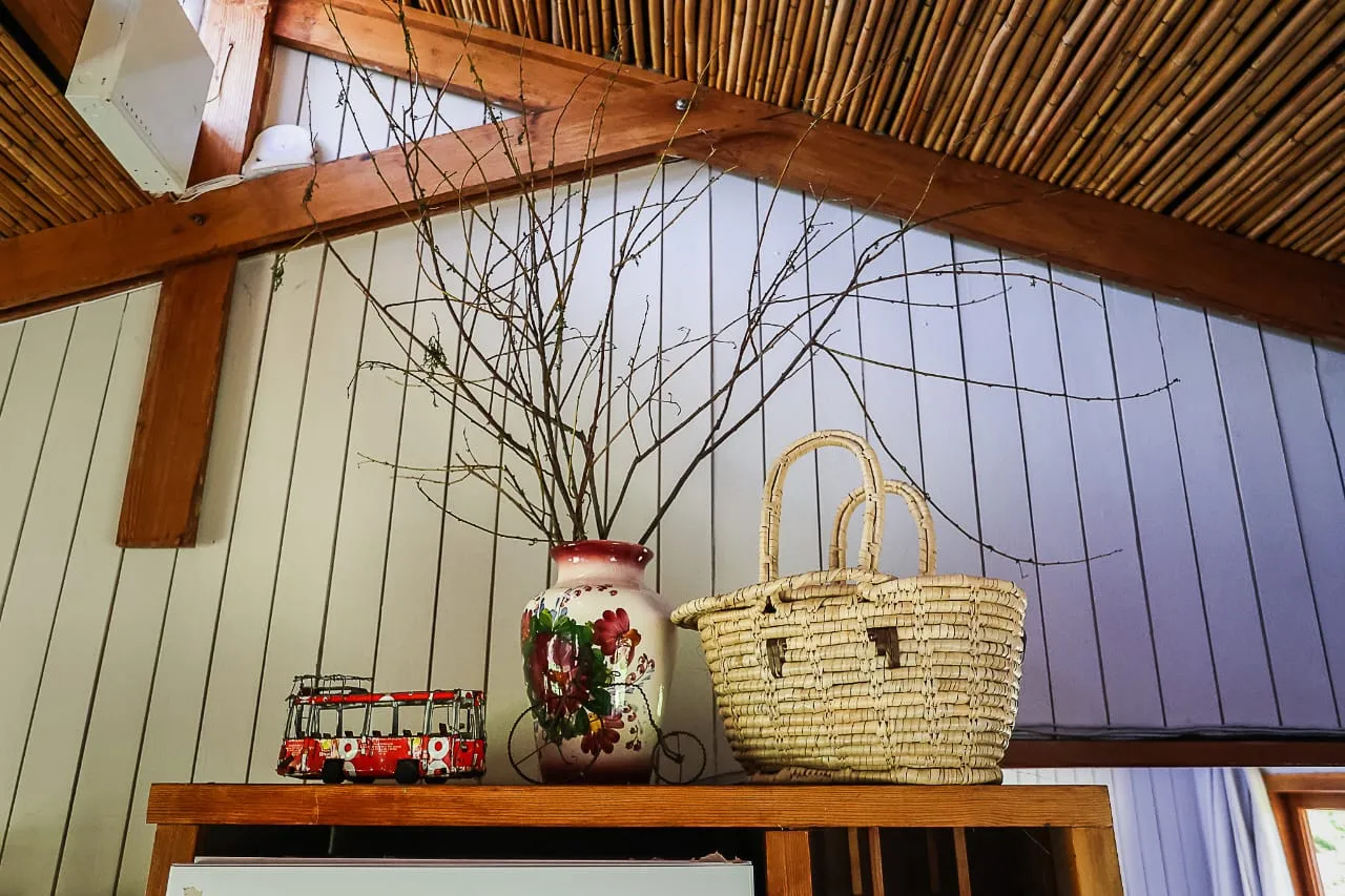 Decorative vase with branches and woven basket on a wooden shelf