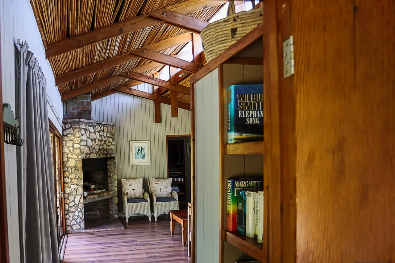 Wooden interior with stone fireplace bookshelves and seating area under a slanted ceiling