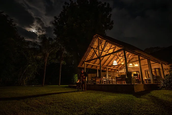 Wooden lodge at night with person standing outside lit interior and full moon