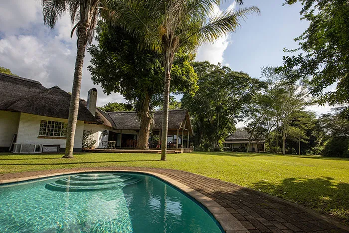 A large house with a swimming pool in a lush green garden