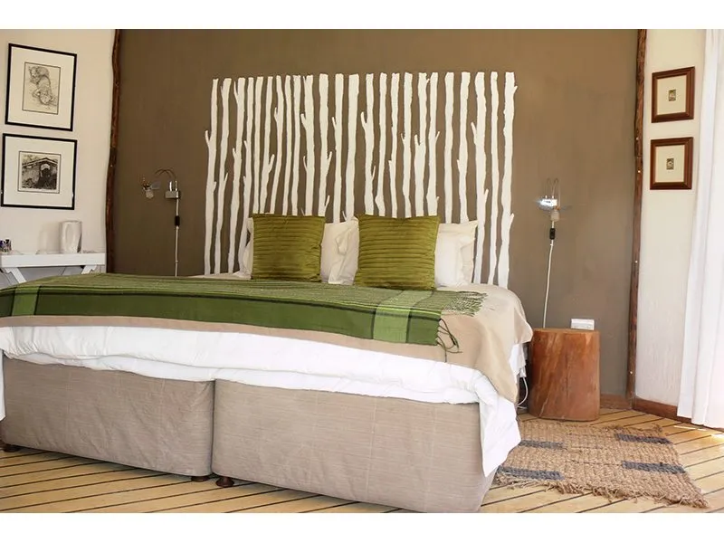 Modern bedroom with a large bed green pillows and wooden bedside table