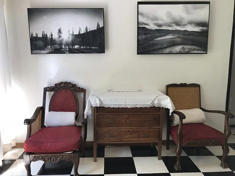 Two red chairs wooden dresser and black and white landscape paintings on white wall