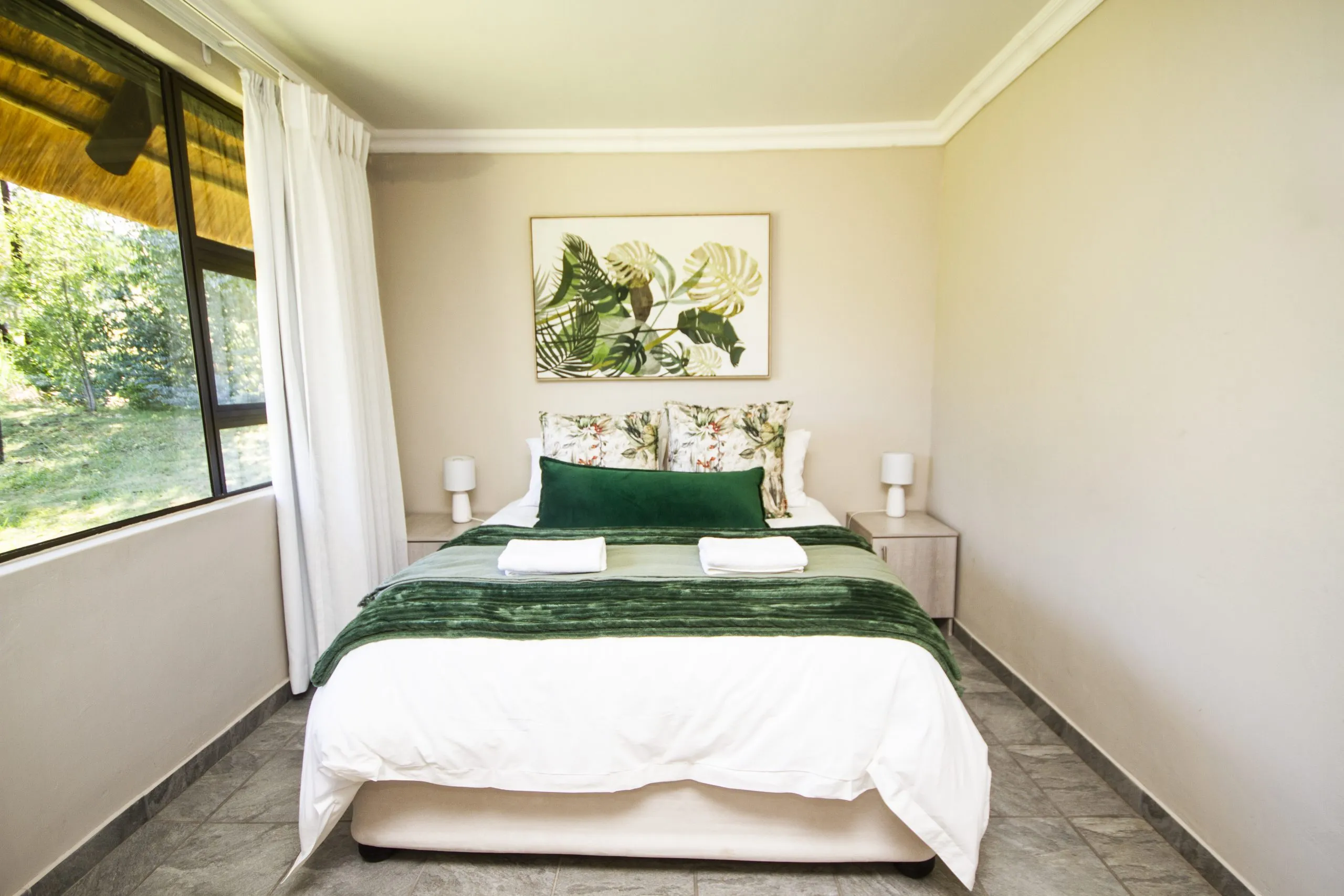 Cozy bedroom with a neatly made bed green accents and large window