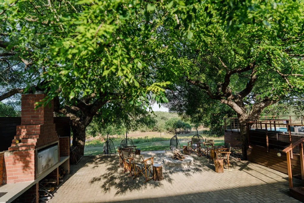 Outdoor seating area with trees chairs and a brick fireplace in a garden