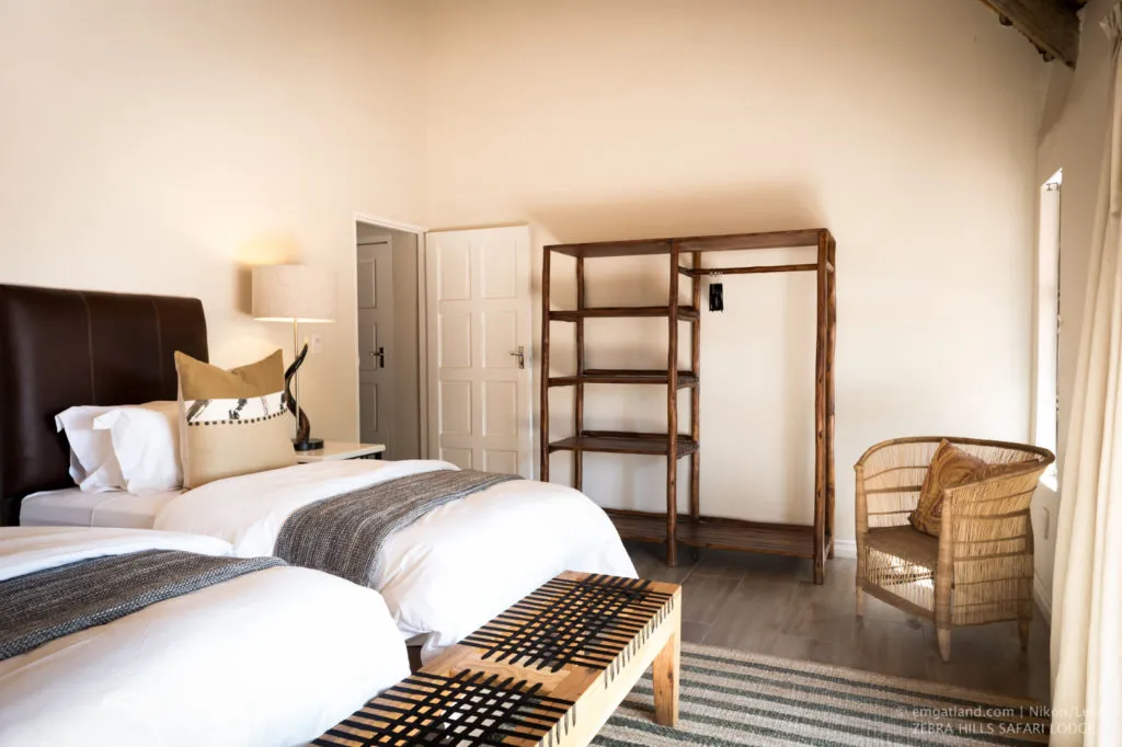 Cozy bedroom with two beds wooden furniture and a wicker chair