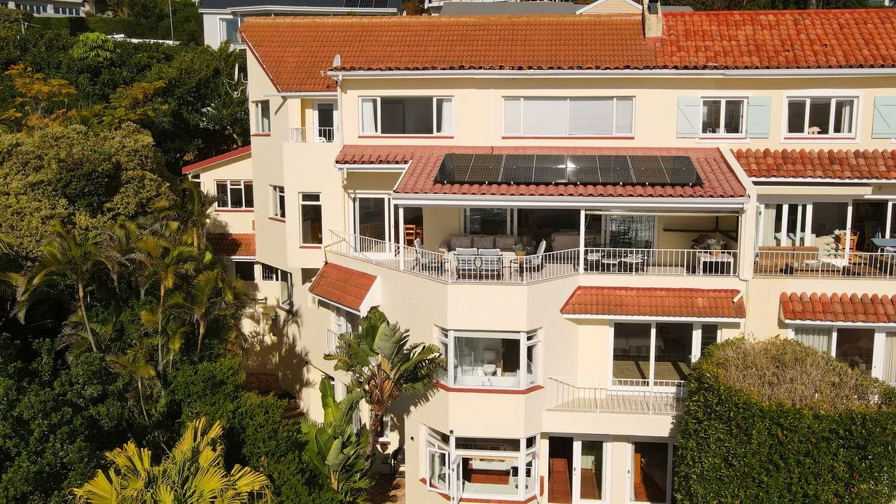Modern threestory house with redtiled roof and balconies surrounded by greenery