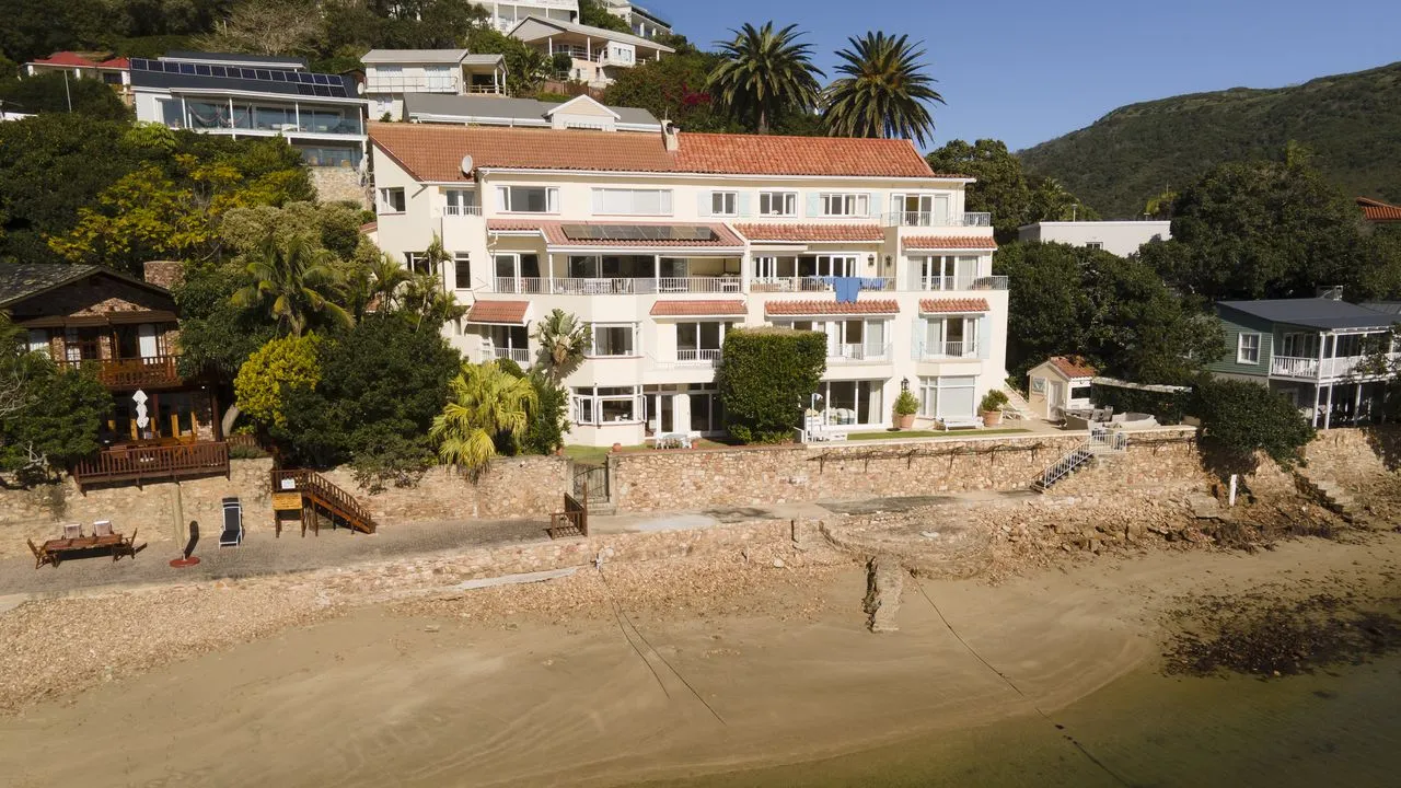 Beachfront house with redtiled roof surrounded by greenery and palm trees