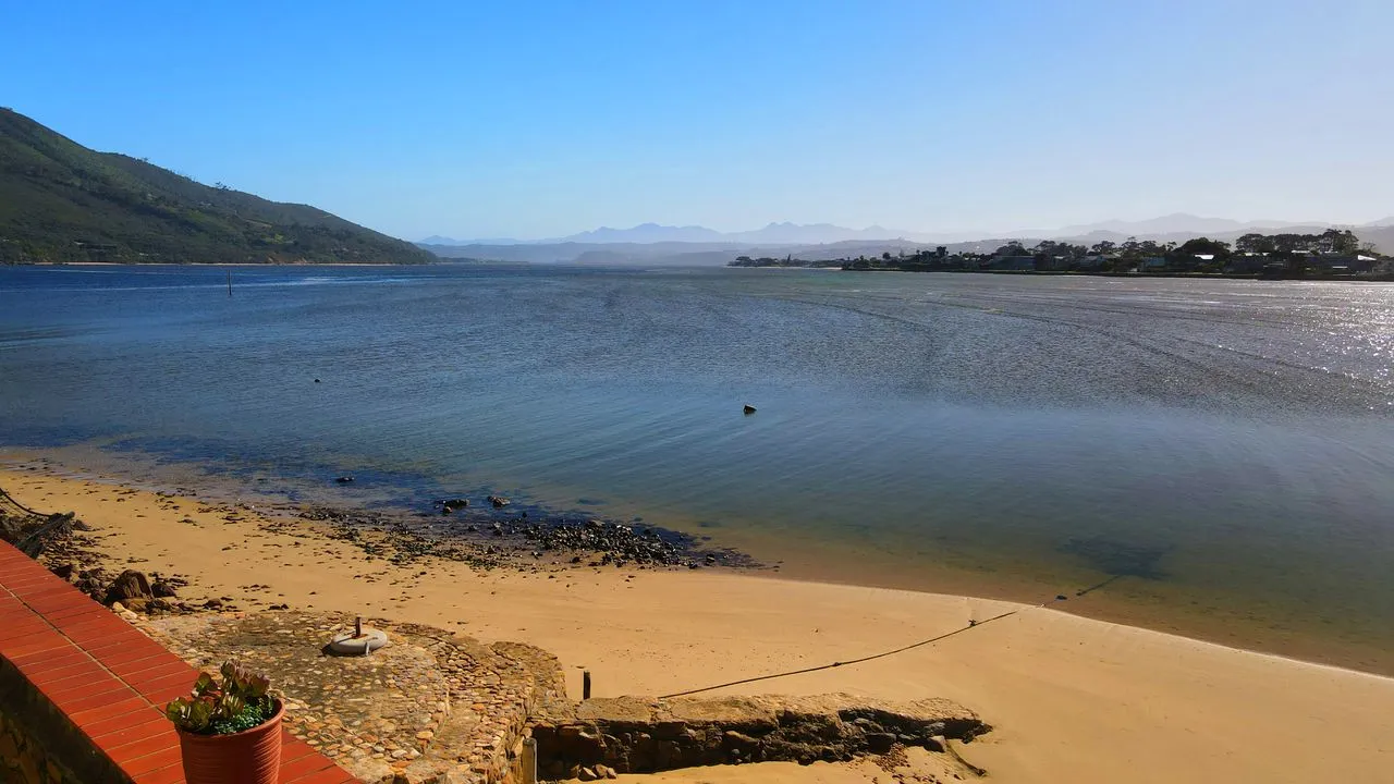 Sandy beach with calm water distant mountains and clear blue sky
