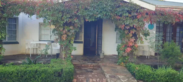 Entrance of a house with ivycovered archway white furniture and garden path