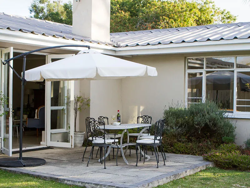 Patio with table chairs and umbrella outside a house with open doors