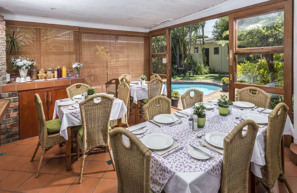 Dining area with tables chairs and a view of a pool and garden