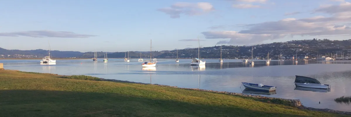 Boats anchored in a calm bay with hills and sky in the background