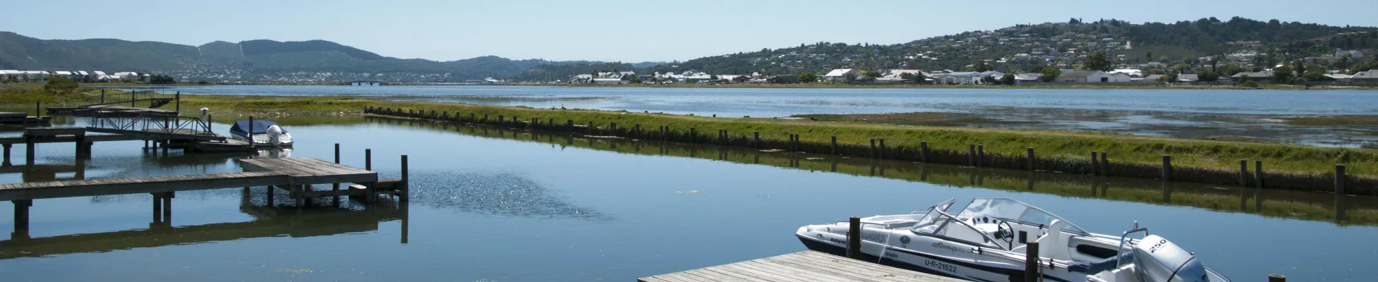 Boat docked at a wooden pier on a calm lake with hills in background