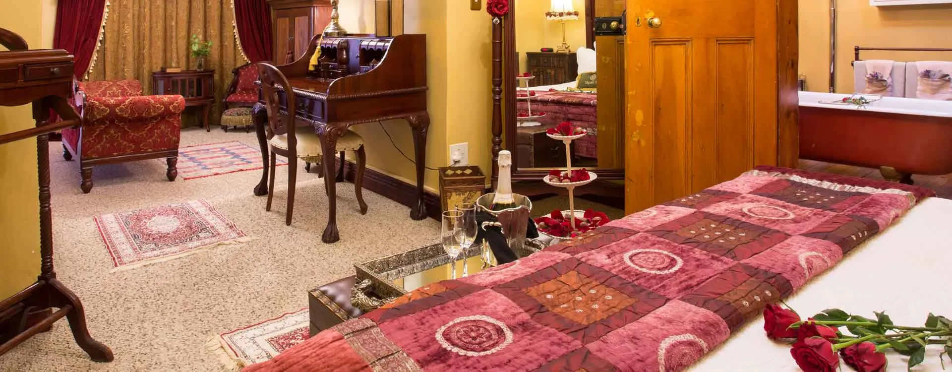 Cozy bedroom with red decor roses on bed and antique furniture