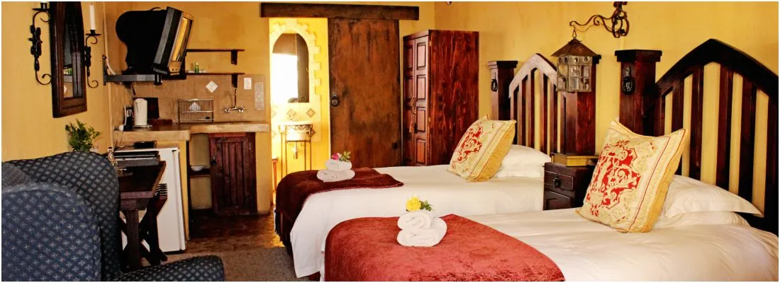 Cozy bedroom with two beds wooden furniture and a small kitchenette