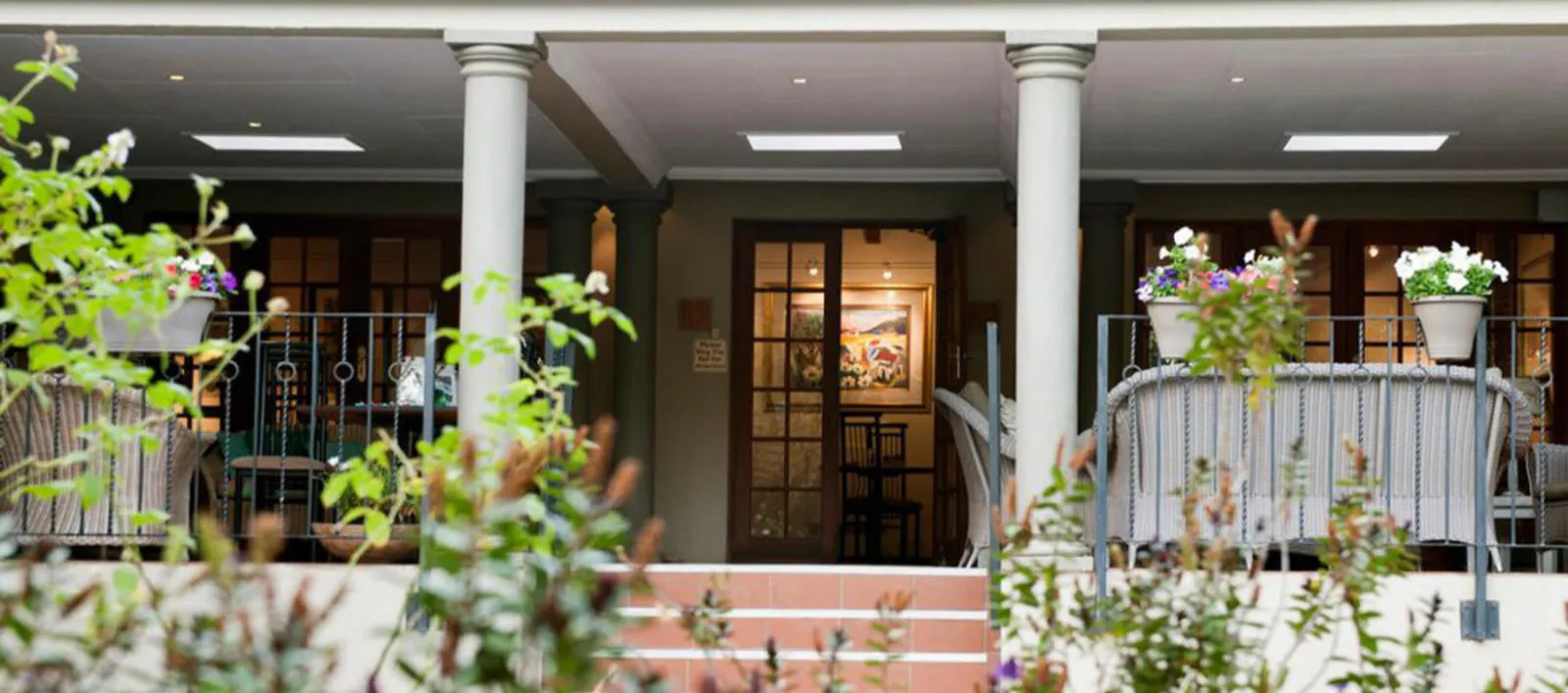 Entrance with columns potted plants and steps leading to a door