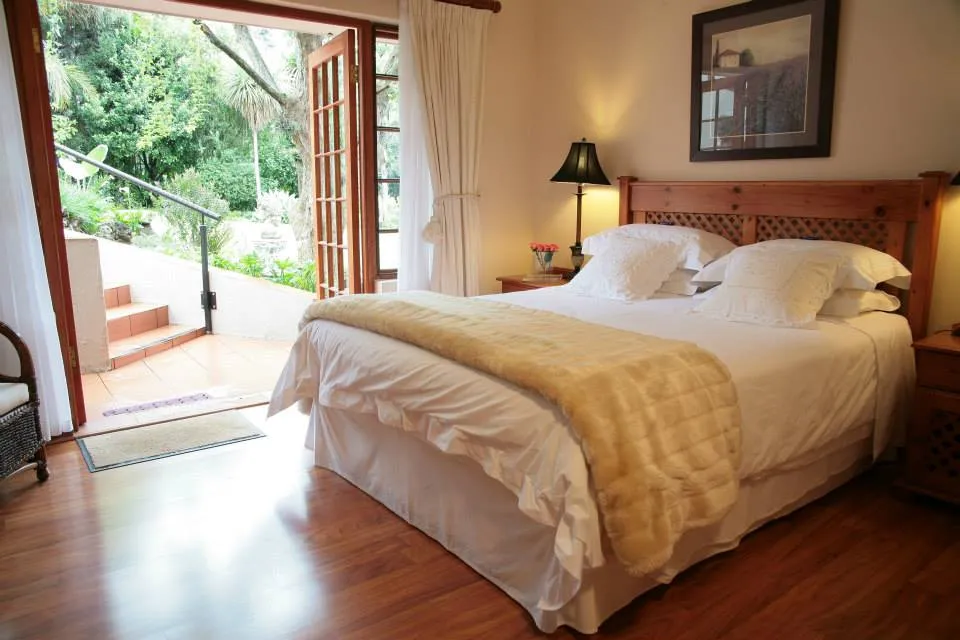 Wooden bedroom with a large bed open door to garden and wooden flooring