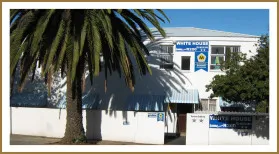 White building with White House sign palm tree and blue sky