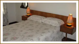 A neatly made bed with floral bedding in a simple bedroom setting