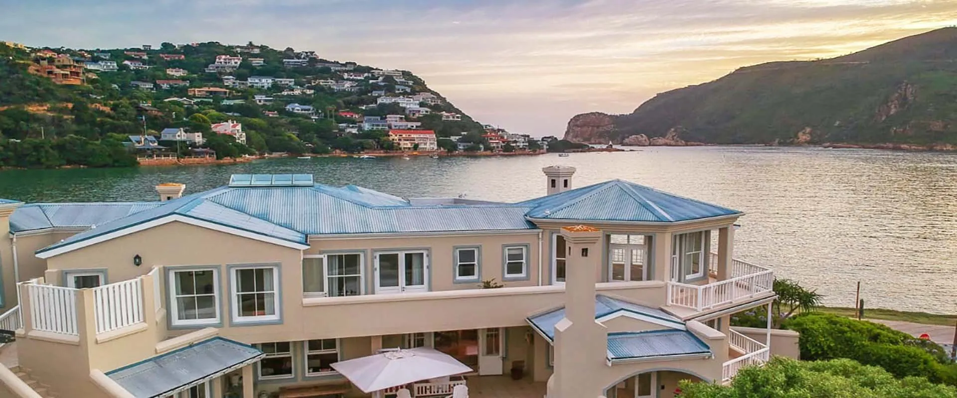 Modern house by the water with hills and sunset in the background