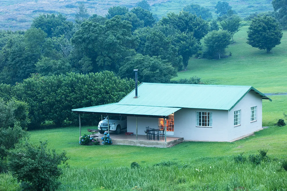 A small house with a green roof in a lush green landscape