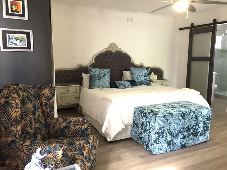 Bedroom with large bed patterned chair and wooden floor featuring a ceiling fan