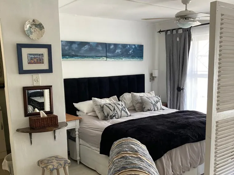 Cozy bedroom with black headboard blue pillows and ceiling fan