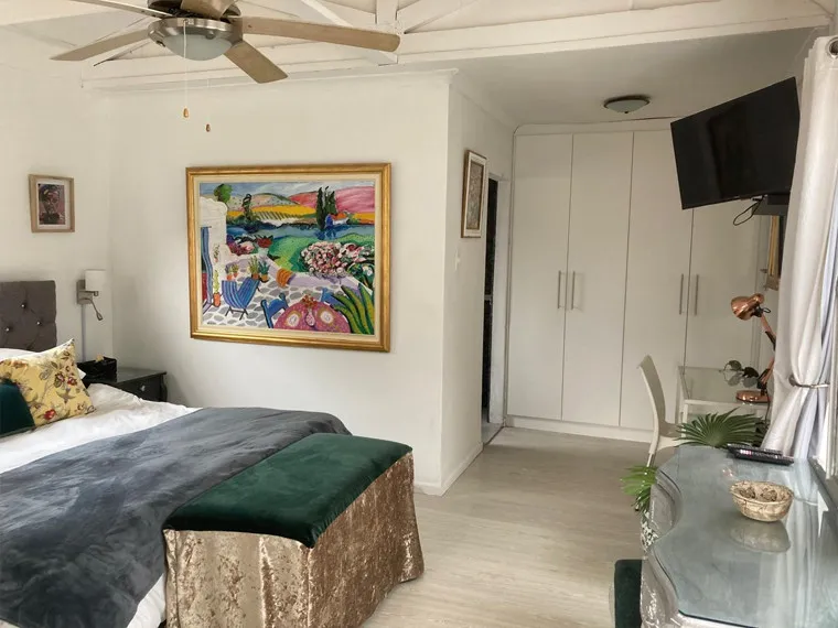 Bedroom with a large colorful painting bed dresser and TV