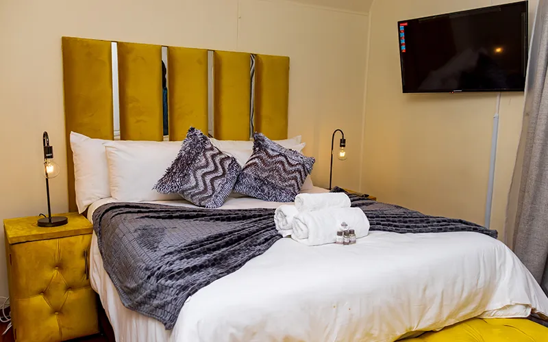 Modern bedroom with a large bed yellow headboard and wallmounted TV