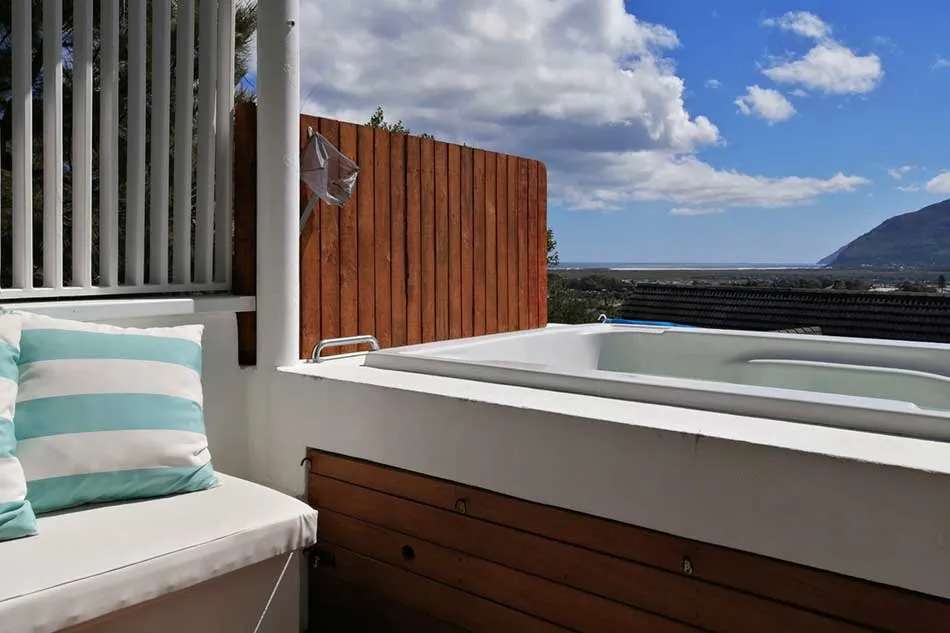 Wooden hot tub on a deck with mountain view and striped cushion