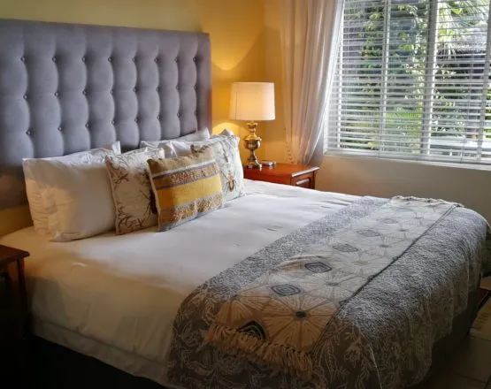Cozy bedroom with a large bed pillows and a bedside lamp near a window