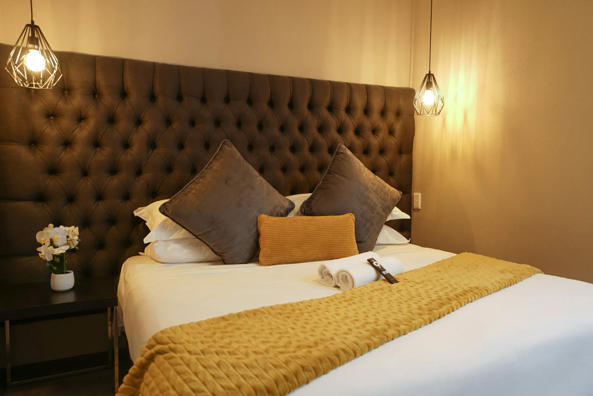 Cozy bedroom with a neatly made bed flowers and pendant lights