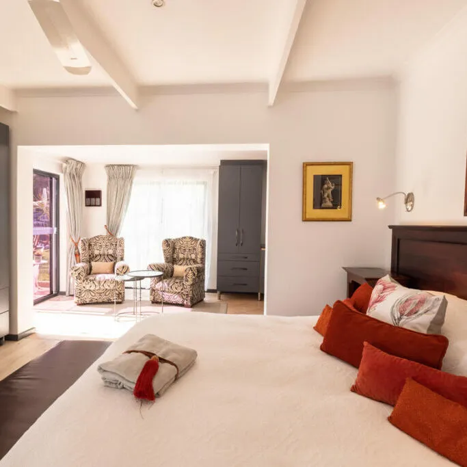 Cozy bedroom with a large bed two armchairs and a framed painting