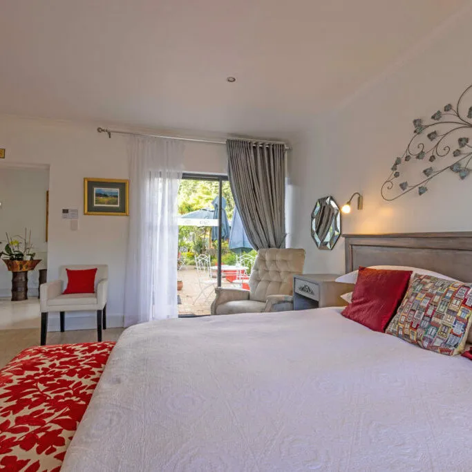 Cozy bedroom with white bed red pillows and large window with curtains