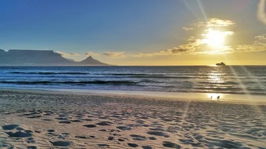 Beach with footprints ocean waves and sunset over distant mountains