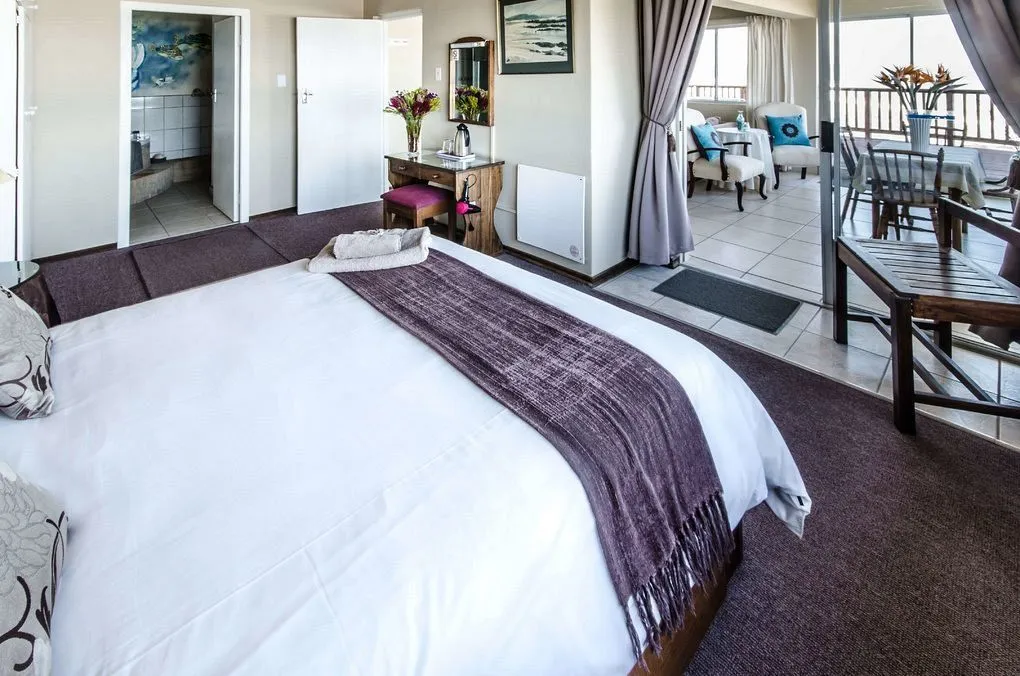 Bedroom with large bed purple throw and view of balcony with seating area