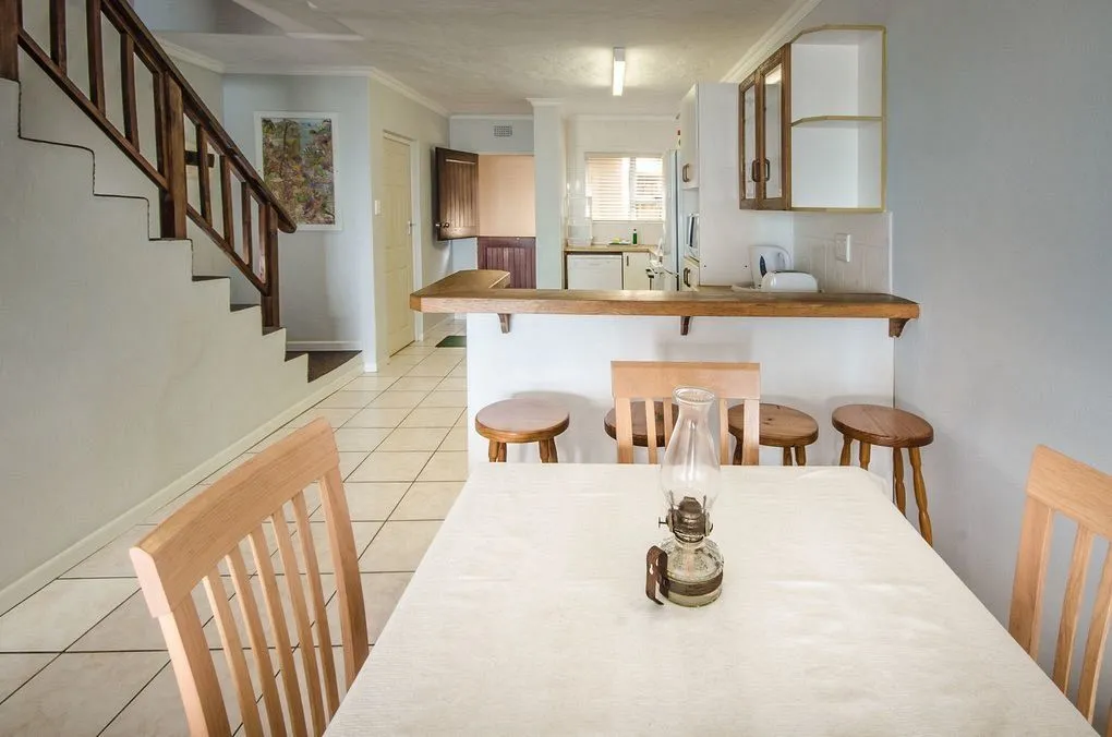 Dining area with table and chairs kitchen in background staircase on left