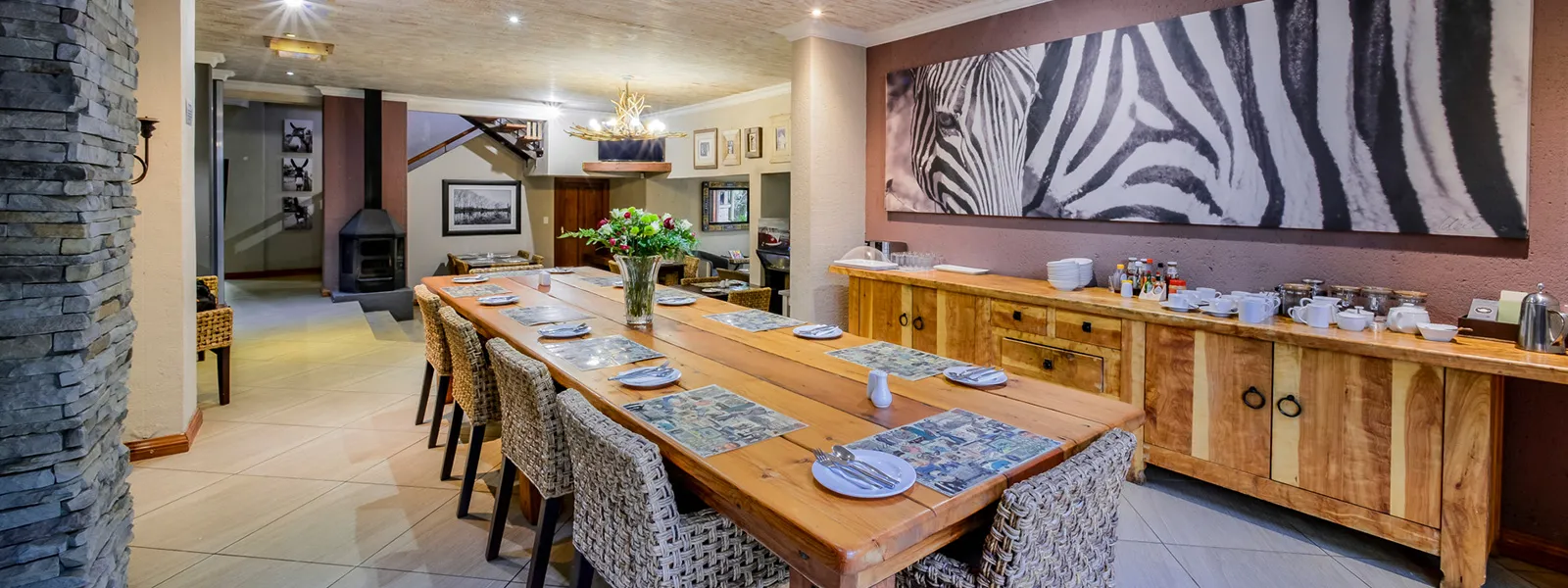 Dining area with long wooden table chairs and zebra artwork on the wall