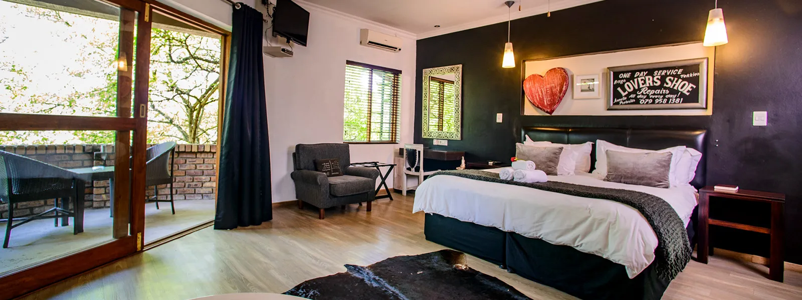 Modern bedroom with large bed armchair and balcony view through glass doors