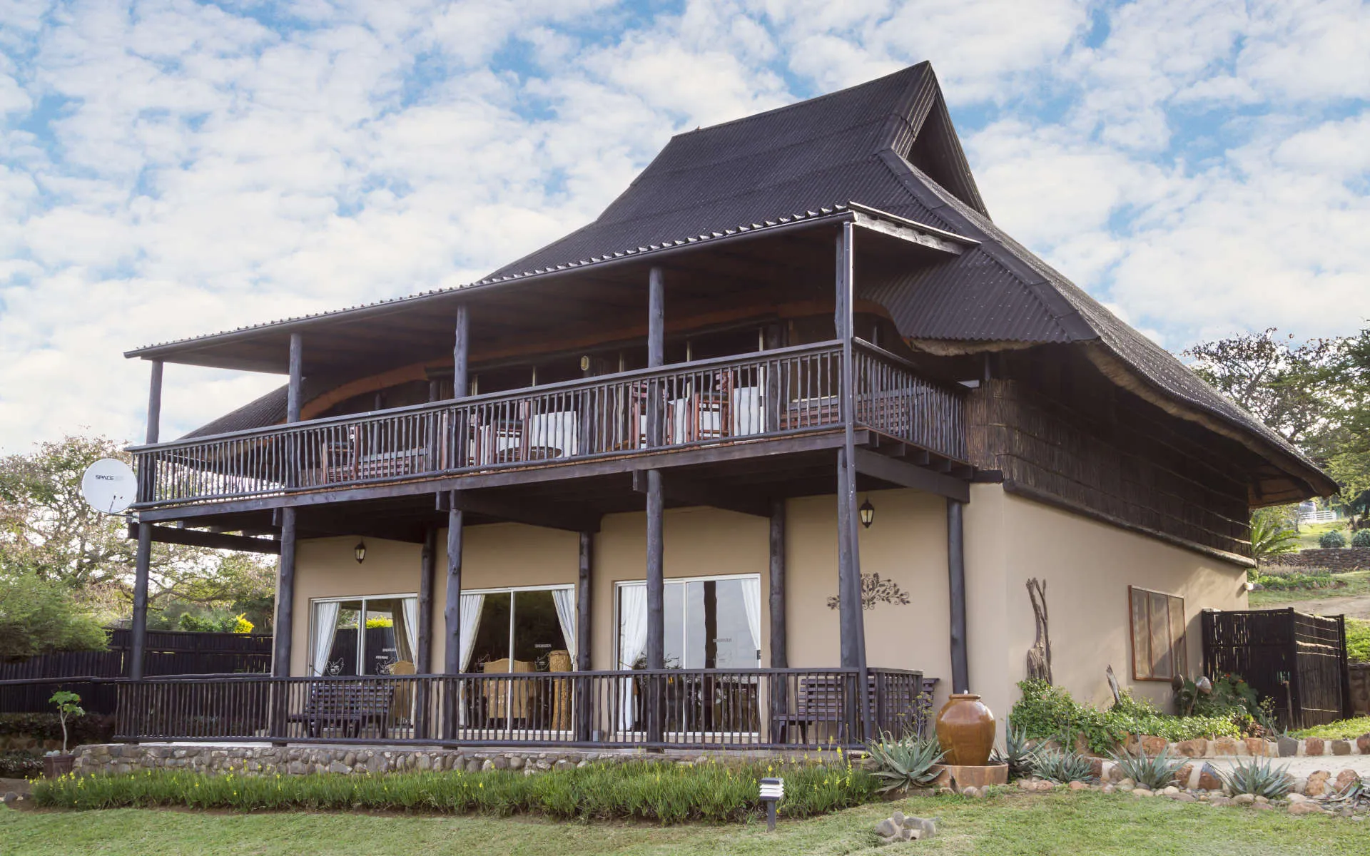 Twostory house with large balconies and a steep dark roof in a garden