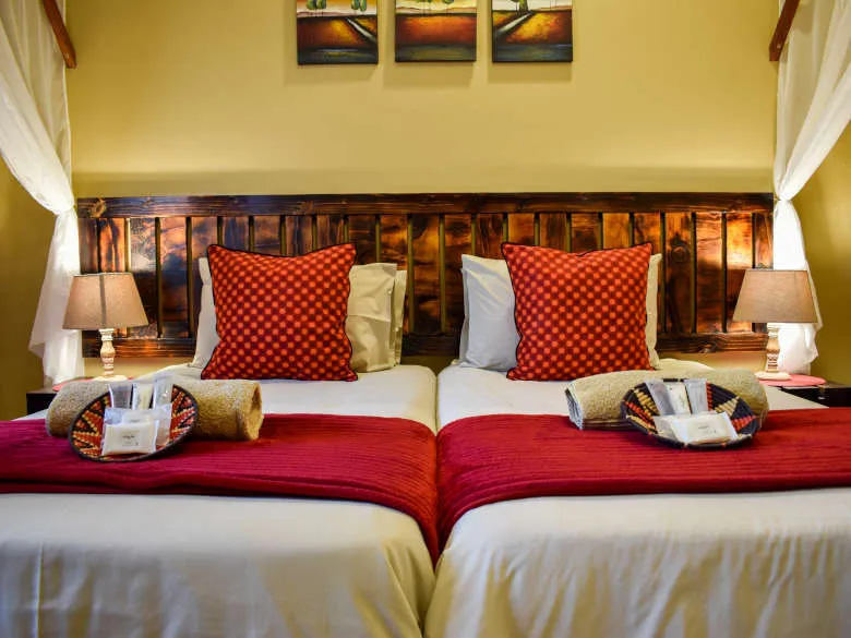 Two neatly made beds with red pillows and blankets in a cozy bedroom