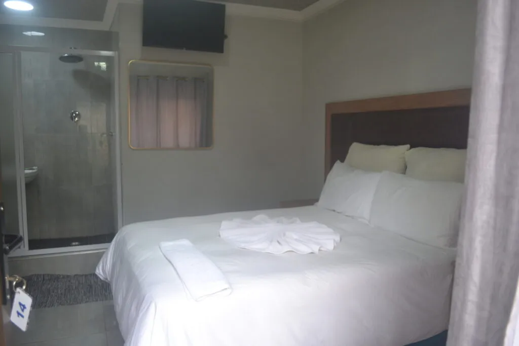 Small bedroom with a double bed and an adjacent shower area