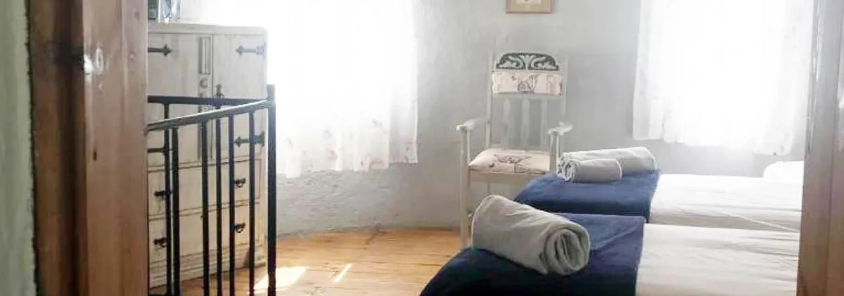 Bedroom with two beds a chair and a wooden dresser by a window