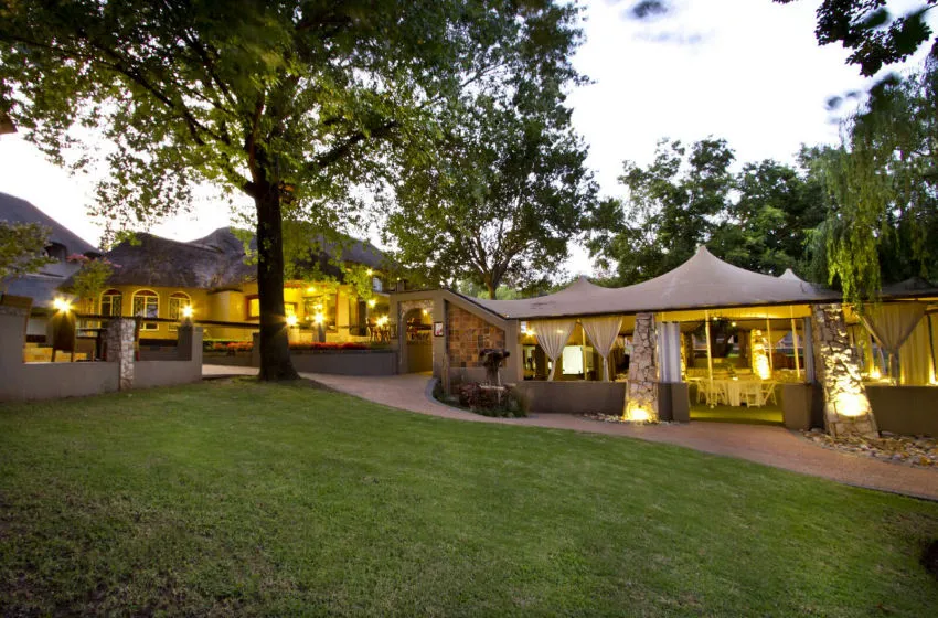 Evening view of a lit outdoor event space with trees and grass