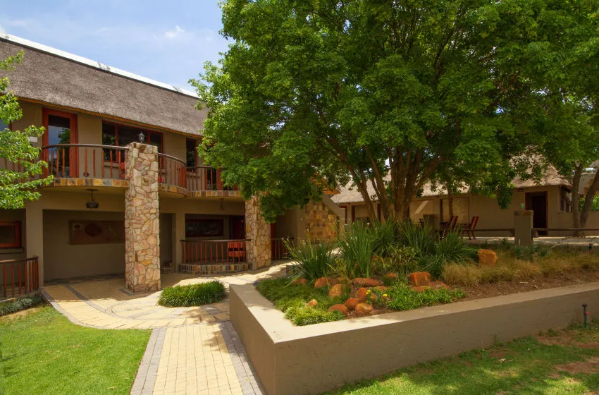 Modern building with stone pillars wooden balconies and lush greenery in front