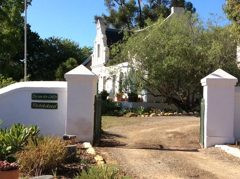 White house with garden and driveway in a sunny green setting