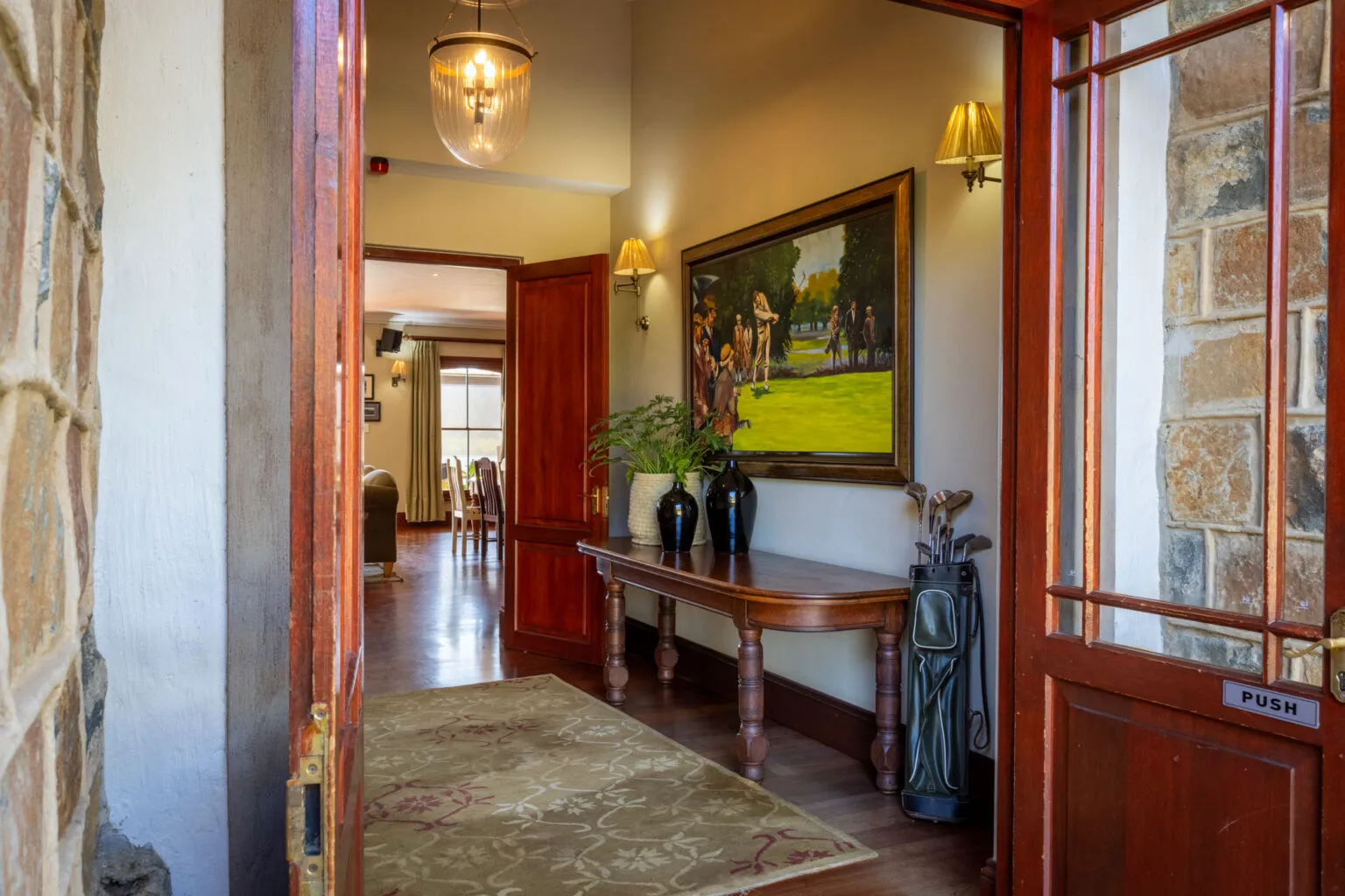 Wooden door opens to hallway with golfthemed decor painting and furniture